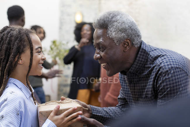 Happy grandfather giving Christmas gift to granddaughter — Stock Photo
