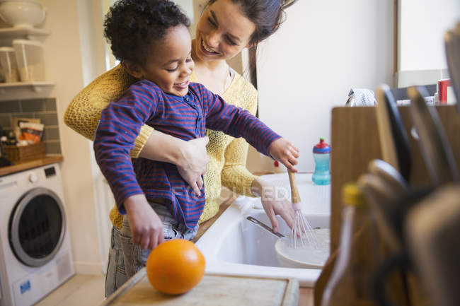 Happy caucasian mother with african american son washing dishware — Stock Photo