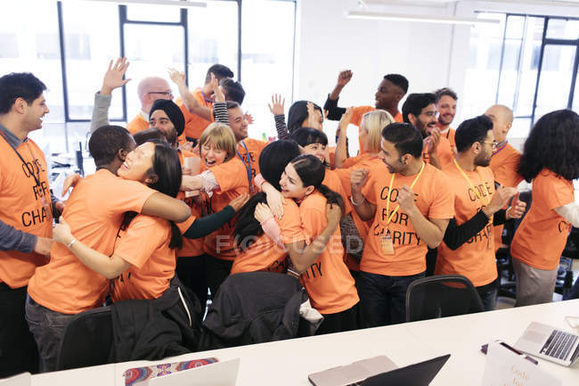 Enthusiastic hackers celebrating, coding for charity at hackathon — Stock Photo