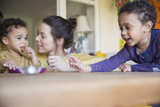 Happy caucasian mother with african american sons at kitchen — Stock Photo