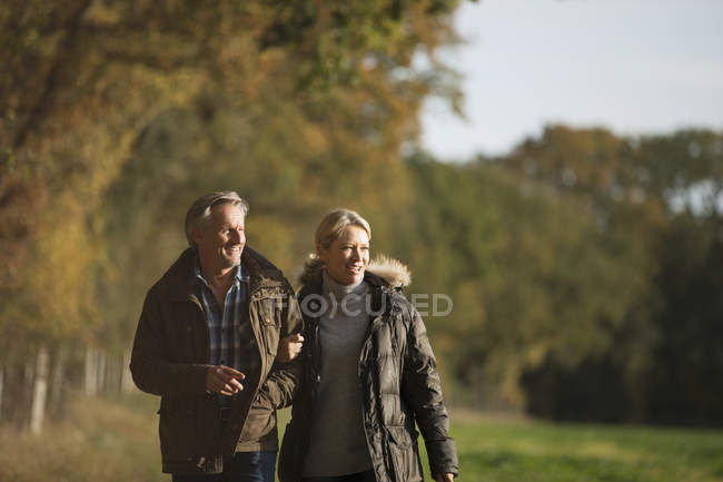 Зрелая кавказская пара, гуляющая вместе в осеннем парке — стоковое фото