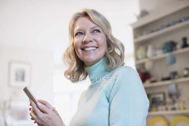 Портрет улыбается, уверенная в себе взрослая женщина смс со смартфона — стоковое фото