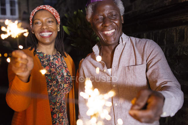 Portrait happy senior father and daughter celebrating with sparklers — Stock Photo