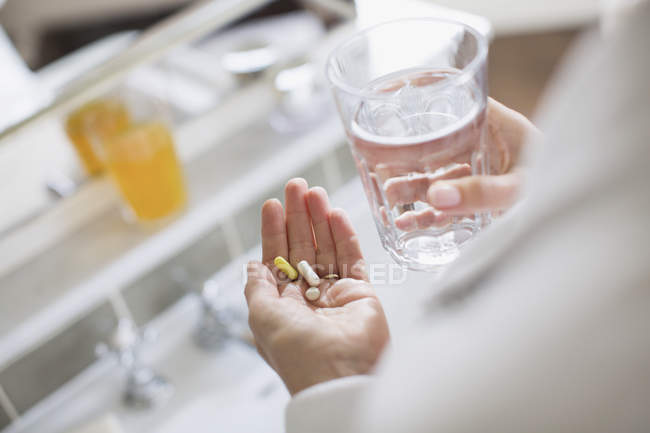 Mulher tomando vitaminas e copo de água — Fotografia de Stock