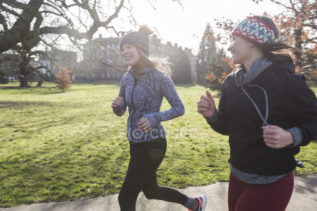 Lächelnde Läuferinnen beim Laufen im sonnigen Park — Stockfoto