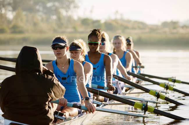 Female rowing team rowing scull on lake — Stock Photo