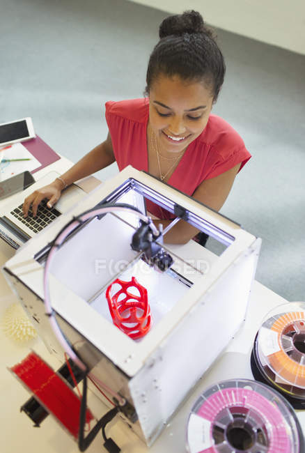 Улыбающаяся женщина-дизайнер смотрит 3D принтер в офисе — стоковое фото