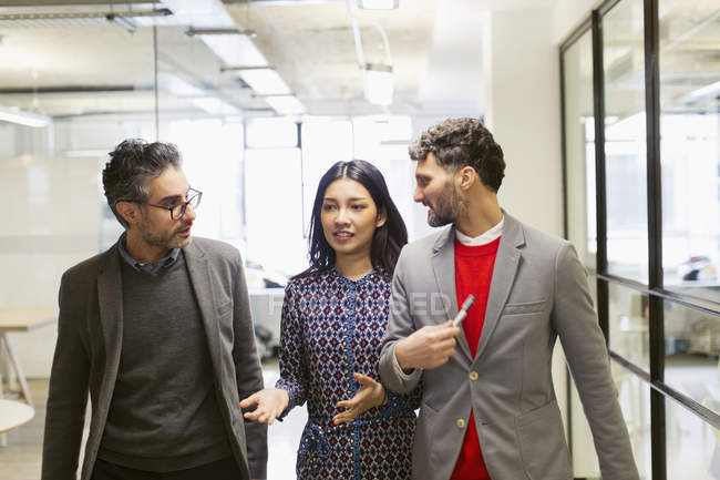 Business people walking and talking in office corridor — Stock Photo