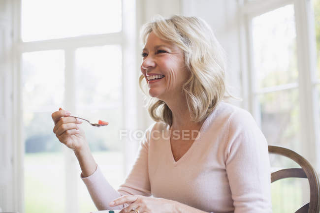 Feliz mulher madura comendo frutas em casa moderna — Fotografia de Stock