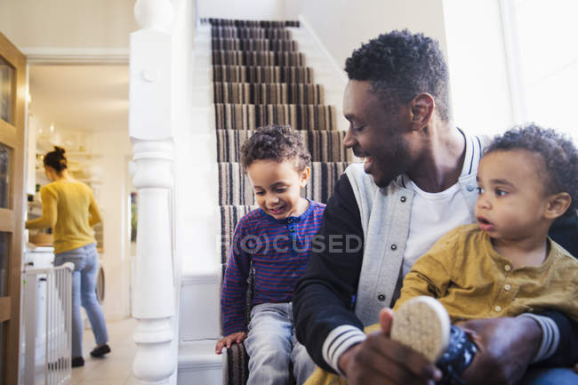 Отец надевает обувь на маленького сына на лестнице — стоковое фото