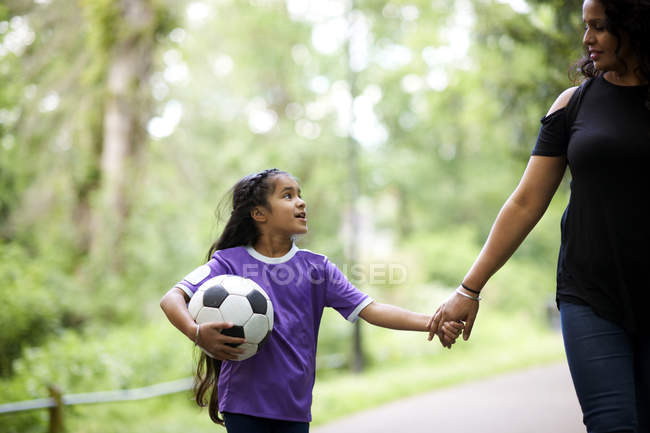 Ласковые мать и дочь с футбольным мячом, держась за руки — стоковое фото