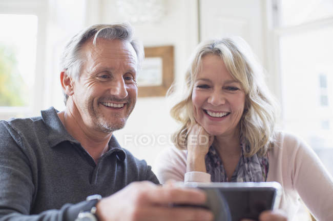 Sourire couple d'âge mûr en utilisant un téléphone intelligent — Photo de stock