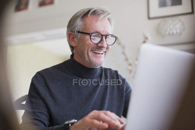 Lächelnde ältere männliche Freiberufler, die am Laptop arbeiten — Stockfoto
