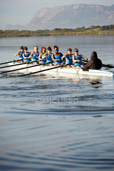 Remadores fêmea scull remo no lago ensolarado — Fotografia de Stock