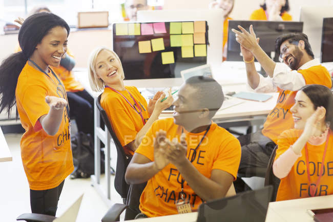 Enthusiastic hackers cheering, coding for charity at hackathon — Stock Photo