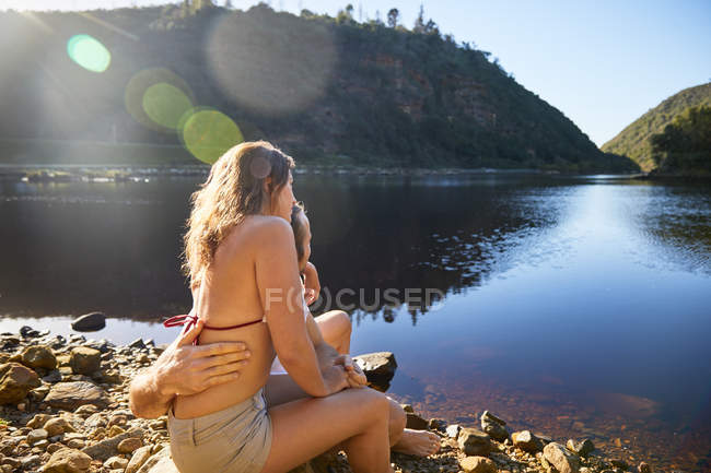 Affectionate couple hugging at sunny summer lake — Stock Photo