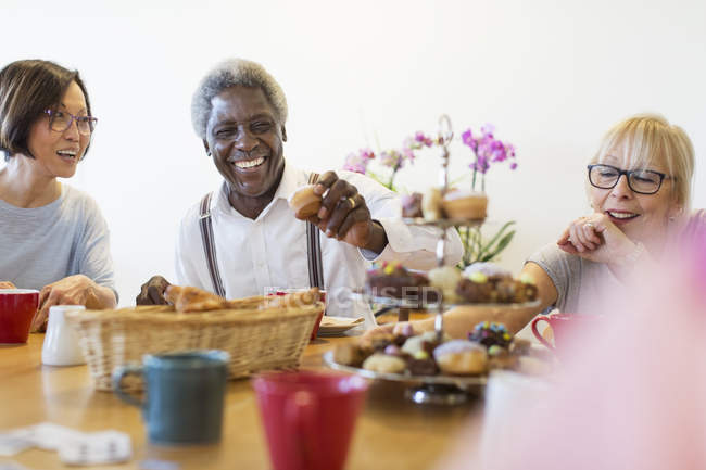 Amigos seniores felizes desfrutando de sobremesas de chá da tarde no centro comunitário — Fotografia de Stock