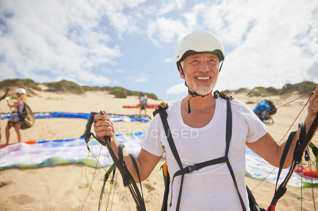 Parapendio maschile maturo sulla spiaggia con attrezzatura — Foto stock