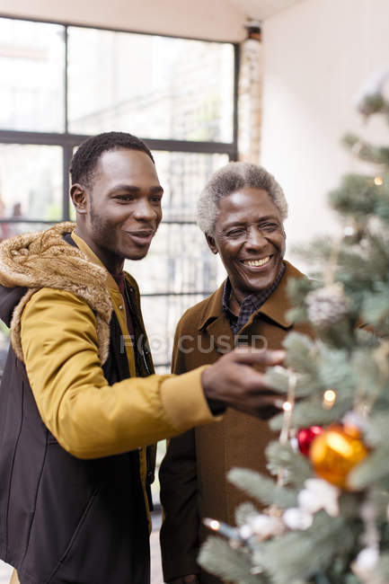 Abuelo y nieto decorando el árbol de Navidad - foto de stock