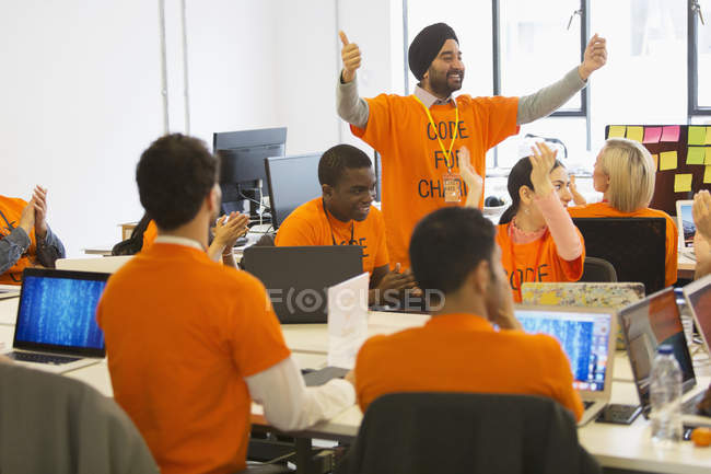 Hackers cheering, coding for charity at hackathon — Stock Photo
