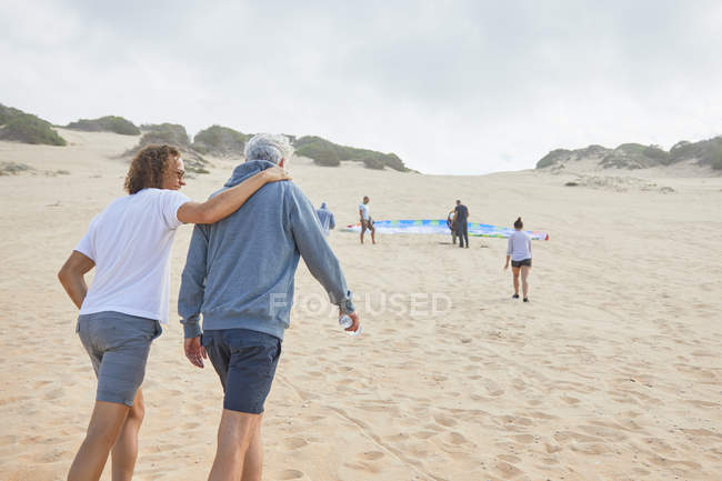 Друзья-парапланеристы, гуляющие по пляжу — стоковое фото