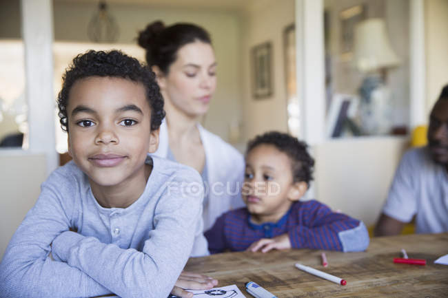 Портрет впевнено хлопчик забарвлення з родиною в таблиці — стокове фото