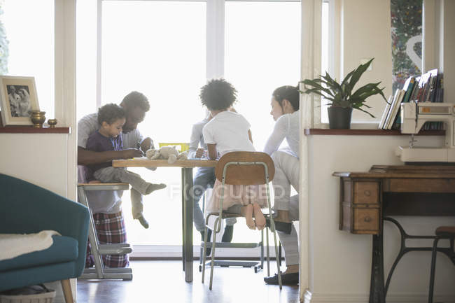 Young family in pajamas coloring at dining table — Stock Photo