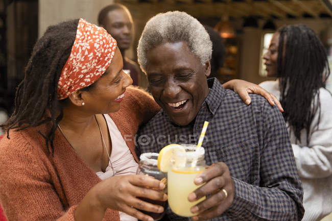 Padre e hija mayores brindando limonada, abrazándose en el patio - foto de stock