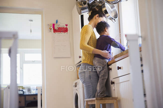 Happy caucasian mother with african american son at kitchen — Stock Photo