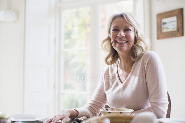 Lächelnde, selbstbewusste reife Frau, die zu Hause isst — Stockfoto