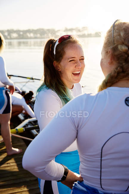 Жінки-веслярі посміхаються і розмовляють на сонячному березі озера — стокове фото