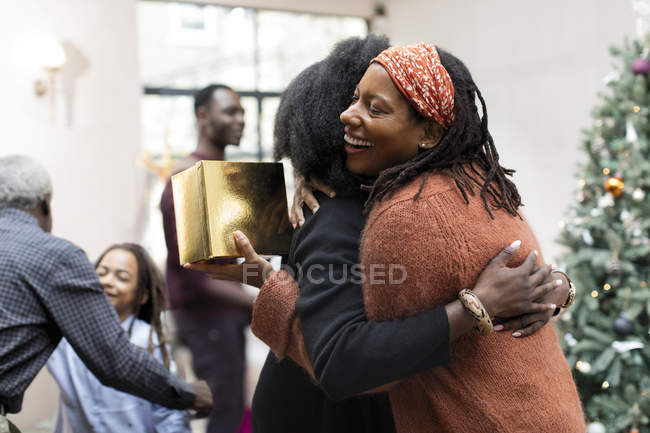 Happy mother and daughter with Christmas gift hugging — Stock Photo