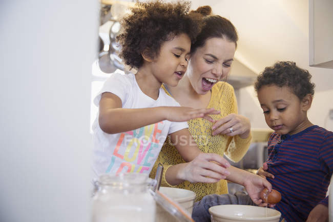 Madre juguetona y niños horneando en la cocina - foto de stock