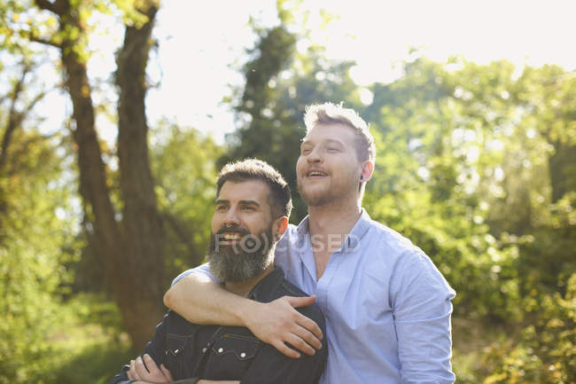 Affectueux mâle gay couple câlins dans sunny parc — Photo de stock