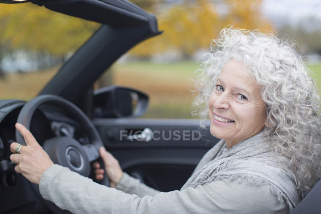Портрет улыбающейся пожилой женщины за рулем кабриолета — стоковое фото