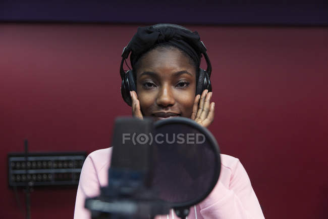 Portrait confident teenage girl musician recording music, singing in sound booth — Stock Photo