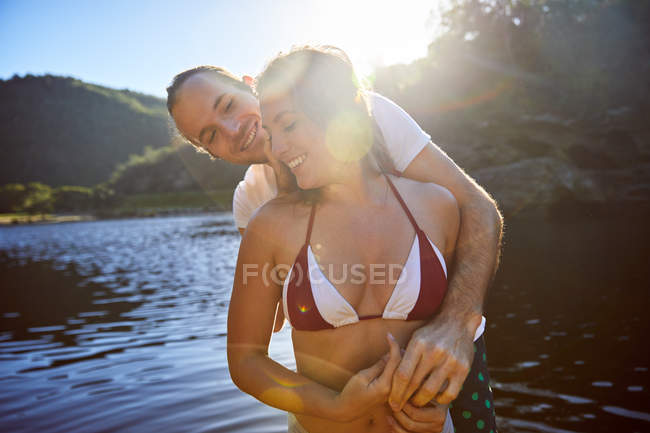 Casal afetuoso abraço no ensolarado lago de verão — Fotografia de Stock