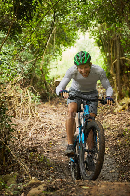 Uomo felice mountain bike sul sentiero nel bosco — Foto stock