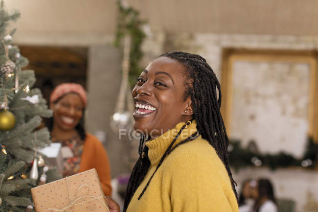 Porträt lachend, begeisterte Frau mit Geschenk am Weihnachtsbaum — Stockfoto
