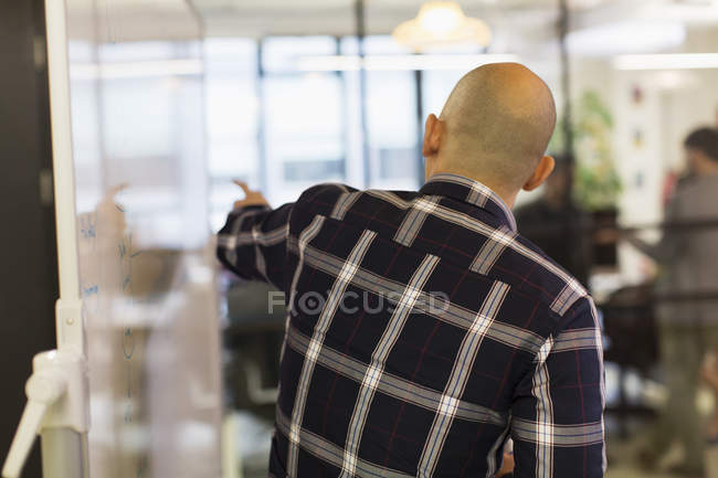 Бизнесмен ведет совещание, указывая на доску — стоковое фото