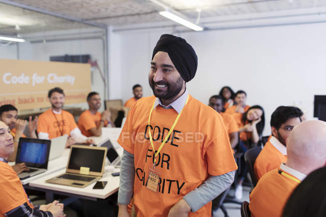 Happy, confident hacker in turban coding for charity at hackathon — Stock Photo