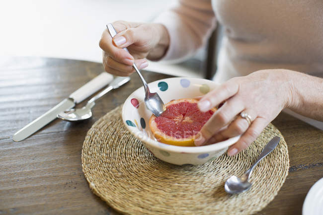 Жінка їсть грейпфрут з ложкою, вид крупним планом — стокове фото