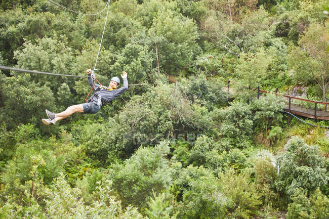 Portrait homme insouciant zip lining au-dessus des arbres — Photo de stock