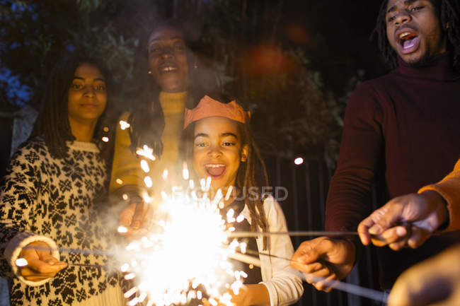 Verspieltes Mädchen mit Wunderkerze feiert mit Familie — Stockfoto