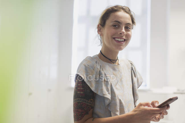 Portrait smiling woman with tattoos texting with smart phone — Stock Photo