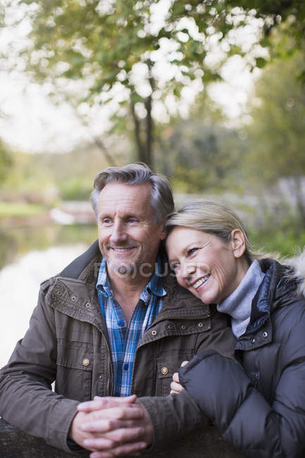 Mature caucasian couple standing by fence together in autumn park — Stock Photo