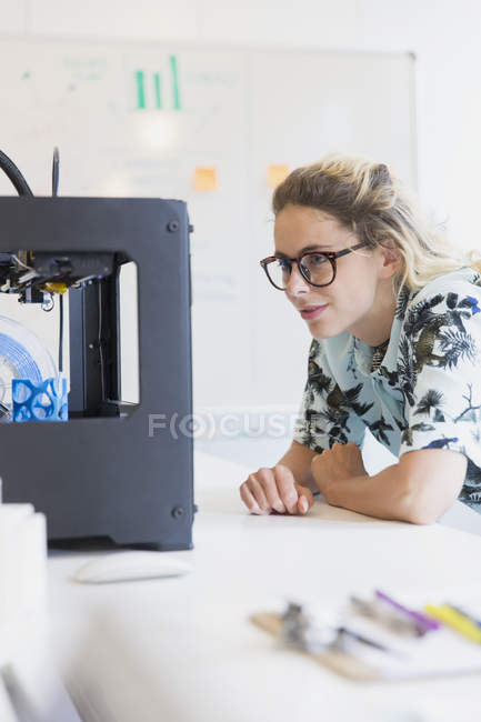 Designer féminin regardant imprimante 3D dans le bureau — Photo de stock
