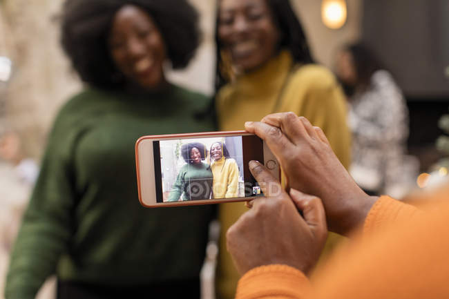 Woman with camera phone photographing mother and daughter — Stock Photo