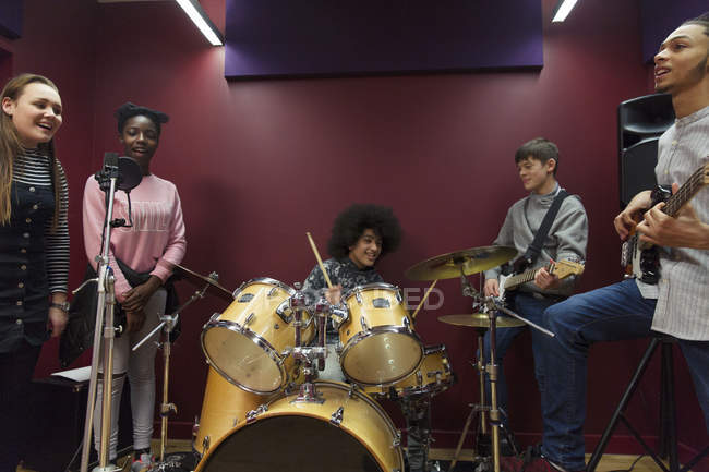 Músicos adolescentes grabando música en cabina de sonido - foto de stock