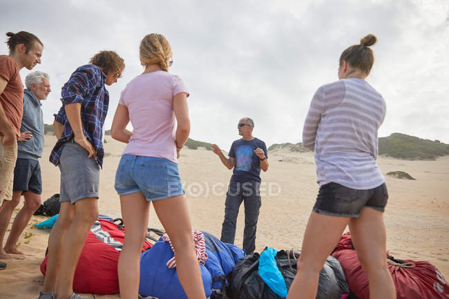 Instrutor de parapente masculino conversando com estudantes na praia — Fotografia de Stock